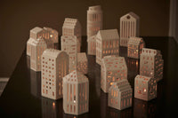 アーバニアは Urban( 都市、都会) が語源のシリーズ。今日も世界のどこかで新たな建物が建てられ、変わっていく現代の街並みと同じように、アーバニアの種類もどんどん広がっています。1 つ1 つハンドメイドでくり抜かれた窓からは、温かく優しい光が漏れだします。夜だけでなく、まだ少し薄暗い朝の時間や夕暮れ時など、時間によって少しずつ表情を変えていくキャンドルの街並みを眺めながら、家の中でゆっくりと流れる時間を楽しんでみるのもおすすめです。