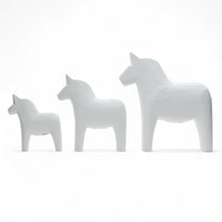 Grannas A. Olsson Hemslojd(グランナス オルソン ヘムスロイド)は、1922年にスウェーデン・ダーラナ地方ヌスナスで創業した世界最古のダラホース工房です。創業者のアンダース オルソン氏は、当初家族経営のパン屋から木工品製造へと転換し、弟らと協力してダラホースの生産を始めました。ひとつずつ選別されたスロースギ材(シルヤン湖周辺の赤松)を使い、木型の挽きから手彫り、下地塗装、さらに熟練のリップル(波模様)ペインターによるフリーハンド装飾を施します。その後、丁寧にニス仕上げされ、赤や白、青など伝統色に彩られた馬たちは、まさに「スウェーデンの象徴」として世界中の家庭や店舗に愛されています。伝統工房としての格式を受け継ぎつつも、パステルやモノトーン、限定柄などを加えることで、現代のインテリアにもマッチするデザイン性も追求しています。