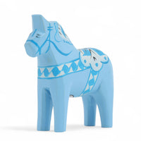 Grannas A. Olsson Hemslojd(グランナス オルソン ヘムスロイド)は、1922年にスウェーデン・ダーラナ地方ヌスナスで創業した世界最古のダラホース工房です。創業者のアンダース オルソン氏は、当初家族経営のパン屋から木工品製造へと転換し、弟らと協力してダラホースの生産を始めました。ひとつずつ選別されたスロースギ材(シルヤン湖周辺の赤松)を使い、木型の挽きから手彫り、下地塗装、さらに熟練のリップル(波模様)ペインターによるフリーハンド装飾を施します。その後、丁寧にニス仕上げされ、赤や白、青など伝統色に彩られた馬たちは、まさに「スウェーデンの象徴」として世界中の家庭や店舗に愛されています。伝統工房としての格式を受け継ぎつつも、パステルやモノトーン、限定柄などを加えることで、現代のインテリアにもマッチするデザイン性も追求しています。