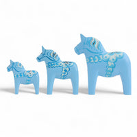 Grannas A. Olsson Hemslojd(グランナス オルソン ヘムスロイド)は、1922年にスウェーデン・ダーラナ地方ヌスナスで創業した世界最古のダラホース工房です。創業者のアンダース オルソン氏は、当初家族経営のパン屋から木工品製造へと転換し、弟らと協力してダラホースの生産を始めました。ひとつずつ選別されたスロースギ材(シルヤン湖周辺の赤松)を使い、木型の挽きから手彫り、下地塗装、さらに熟練のリップル(波模様)ペインターによるフリーハンド装飾を施します。その後、丁寧にニス仕上げされ、赤や白、青など伝統色に彩られた馬たちは、まさに「スウェーデンの象徴」として世界中の家庭や店舗に愛されています。伝統工房としての格式を受け継ぎつつも、パステルやモノトーン、限定柄などを加えることで、現代のインテリアにもマッチするデザイン性も追求しています。