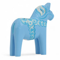 Grannas A. Olsson Hemslojd(グランナス オルソン ヘムスロイド)は、1922年にスウェーデン・ダーラナ地方ヌスナスで創業した世界最古のダラホース工房です。創業者のアンダース オルソン氏は、当初家族経営のパン屋から木工品製造へと転換し、弟らと協力してダラホースの生産を始めました。ひとつずつ選別されたスロースギ材(シルヤン湖周辺の赤松)を使い、木型の挽きから手彫り、下地塗装、さらに熟練のリップル(波模様)ペインターによるフリーハンド装飾を施します。その後、丁寧にニス仕上げされ、赤や白、青など伝統色に彩られた馬たちは、まさに「スウェーデンの象徴」として世界中の家庭や店舗に愛されています。伝統工房としての格式を受け継ぎつつも、パステルやモノトーン、限定柄などを加えることで、現代のインテリアにもマッチするデザイン性も追求しています。