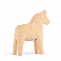 Grannas A. Olsson Hemslojd(グランナス オルソン ヘムスロイド)は、1922年にスウェーデン・ダーラナ地方ヌスナスで創業した世界最古のダラホース工房です。創業者のアンダース オルソン氏は、当初家族経営のパン屋から木工品製造へと転換し、弟らと協力してダラホースの生産を始めました。ひとつずつ選別されたスロースギ材(シルヤン湖周辺の赤松)を使い、木型の挽きから手彫り、下地塗装、さらに熟練のリップル(波模様)ペインターによるフリーハンド装飾を施します。その後、丁寧にニス仕上げされ、赤や白、青など伝統色に彩られた馬たちは、まさに「スウェーデンの象徴」として世界中の家庭や店舗に愛されています。伝統工房としての格式を受け継ぎつつも、パステルやモノトーン、限定柄などを加えることで、現代のインテリアにもマッチするデザイン性も追求しています。