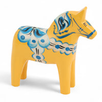 Grannas A. Olsson Hemslojd(グランナス オルソン ヘムスロイド)は、1922年にスウェーデン・ダーラナ地方ヌスナスで創業した世界最古のダラホース工房です。創業者のアンダース オルソン氏は、当初家族経営のパン屋から木工品製造へと転換し、弟らと協力してダラホースの生産を始めました。ひとつずつ選別されたスロースギ材(シルヤン湖周辺の赤松)を使い、木型の挽きから手彫り、下地塗装、さらに熟練のリップル(波模様)ペインターによるフリーハンド装飾を施します。その後、丁寧にニス仕上げされ、赤や白、青など伝統色に彩られた馬たちは、まさに「スウェーデンの象徴」として世界中の家庭や店舗に愛されています。伝統工房としての格式を受け継ぎつつも、パステルやモノトーン、限定柄などを加えることで、現代のインテリアにもマッチするデザイン性も追求しています。