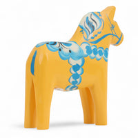 Grannas A. Olsson Hemslojd(グランナス オルソン ヘムスロイド)は、1922年にスウェーデン・ダーラナ地方ヌスナスで創業した世界最古のダラホース工房です。創業者のアンダース オルソン氏は、当初家族経営のパン屋から木工品製造へと転換し、弟らと協力してダラホースの生産を始めました。ひとつずつ選別されたスロースギ材(シルヤン湖周辺の赤松)を使い、木型の挽きから手彫り、下地塗装、さらに熟練のリップル(波模様)ペインターによるフリーハンド装飾を施します。その後、丁寧にニス仕上げされ、赤や白、青など伝統色に彩られた馬たちは、まさに「スウェーデンの象徴」として世界中の家庭や店舗に愛されています。伝統工房としての格式を受け継ぎつつも、パステルやモノトーン、限定柄などを加えることで、現代のインテリアにもマッチするデザイン性も追求しています。