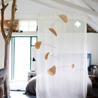 Flensted Mobiles(フレンステッド・モビール)は、1953年創業のデンマーク発・モビール専門ブランド。北欧デザインの文脈に立脚し、造形・質量配分・回転慣性を最適化して、わずかな気流でも自律的に表情を変える構成美を追求します。各パーツは重心とトルクの釣り合いを精密に設計し、静止と運動のあいだを往還する“動く彫刻”として空間に時間軸を付与。代表作「Lucky Storks」から幾何学、鳥類、気球まで多彩で、紙・ステンレス・木材の軽量構造は施工負荷が小さく、住宅・商業・ホスピタリティ・キッズ空間に適合します。現在もデンマーク国内で手作業組立・品質管理を徹底し、視覚ノイズを抑えた運動リズムが集中・鎮静・遊び心をもたらします。北欧インテリアの天井飾りや吊り下げモビールとして、リビング・子供部屋・出産祝いギフトに最適なデンマーク製の正規品です。