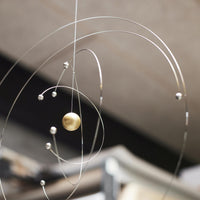 Flensted Mobiles(フレンステッド・モビール)は、1953年創業のデンマーク発・モビール専門ブランド。北欧デザインの文脈に立脚し、造形・質量配分・回転慣性を最適化して、わずかな気流でも自律的に表情を変える構成美を追求します。各パーツは重心とトルクの釣り合いを精密に設計し、静止と運動のあいだを往還する“動く彫刻”として空間に時間軸を付与。代表作「Lucky Storks」から幾何学、鳥類、気球まで多彩で、紙・ステンレス・木材の軽量構造は施工負荷が小さく、住宅・商業・ホスピタリティ・キッズ空間に適合します。現在もデンマーク国内で手作業組立・品質管理を徹底し、視覚ノイズを抑えた運動リズムが集中・鎮静・遊び心をもたらします。北欧インテリアの天井飾りや吊り下げモビールとして、リビング・子供部屋・出産祝いギフトに最適なデンマーク製の正規品です。