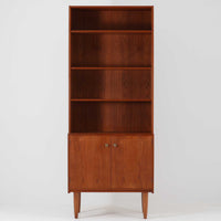 デンマークのHorsens Mobelfabrik社によるディスプレイシェルフは、温かみあるチーク材を使用した端正な佇まいが魅力の一台です。上段には可動棚が4枚備わっており、書籍やオブジェなどのディスプレイに最適です。下段は観音開きの収納扉付きで、見せる収納と隠す収納を両立。すっきりとした脚部構造と洗練された金属取手がアクセントとなり、北欧らしい実用性と美しさを兼ね備えたビンテージ家具です。