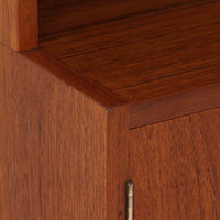 デンマークのHorsens Mobelfabrik社によるディスプレイシェルフは、温かみあるチーク材を使用した端正な佇まいが魅力の一台です。上段には可動棚が4枚備わっており、書籍やオブジェなどのディスプレイに最適です。下段は観音開きの収納扉付きで、見せる収納と隠す収納を両立。すっきりとした脚部構造と洗練された金属取手がアクセントとなり、北欧らしい実用性と美しさを兼ね備えたビンテージ家具です。