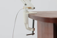 デンマークより買い付けたLouis Poulsen社製のデスクランプです。現行品では販売されていない希少なモデルで、シンプルながら機能的なデザインが特徴です。クランプタイプのため、置く場所を選ばず使用可能。最大板厚5cmまでの場所に取り付けることができるため、デスクやテーブルにしっかり固定してお使いいただけます。アーム部分は可動式で、光の角度を自由に調整できる設計になっており、デスクワークや読書、細かい作業にも最適です。ビンテージ品ならではの風合いが魅力的で、使い込まれたスチールの質感が独特の味わいを醸し出しています。