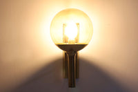 こちらは、Sven mejlstromによってデザインされた1960年代のウォールランプです。Sven mejlstromは、ノルウェーの照明デザイナーとして知られ、シンプルで機能的な美しさを追求したデザインを手掛けました。このランプは、真鍮とクリアガラスを組み合わせた美しいデザインが特徴で、ビンテージ品ならではの風合いが感じられます。大きなボール状のガラスシェードは光を柔らかく拡散し、空間に温かみと上品さを加えます。経年変化による真鍮部分の風合いも、時間を経た美しさを感じさせる魅力的な要素です。シンプルでありながらも印象的なこのウォールランプは、どんなインテリアにも調和し、エレガントなアクセントを与えてくれる一品です。