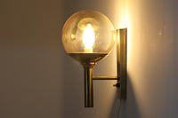 こちらは、Sven mejlstromによってデザインされた1960年代のウォールランプです。Sven mejlstromは、ノルウェーの照明デザイナーとして知られ、シンプルで機能的な美しさを追求したデザインを手掛けました。このランプは、真鍮とクリアガラスを組み合わせた美しいデザインが特徴で、ビンテージ品ならではの風合いが感じられます。大きなボール状のガラスシェードは光を柔らかく拡散し、空間に温かみと上品さを加えます。経年変化による真鍮部分の風合いも、時間を経た美しさを感じさせる魅力的な要素です。シンプルでありながらも印象的なこのウォールランプは、どんなインテリアにも調和し、エレガントなアクセントを与えてくれる一品です。