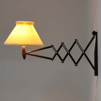 Erik Hansen(エリック・ハンセン)がデザインし、Le Klint(レ・クリント)より発表されたブラケットランプModel 332です。温かみのあるローズウッド材のアームと、職人技によるプリーツシェードの組み合わせが美しく、北欧らしい柔らかな光を演出します。アコーディオン式のアームは伸縮可能で、ベッドサイドやリビングの読書灯としても最適です。経年により味わいを増した木部とオリジナルシェードが、ビンテージならではの存在感を放ちます。ローズウッド材での展開はビンテージ品でのみ入手可能で、現行品には存在しない希少な一品です。