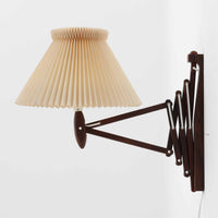 Erik Hansen(エリック・ハンセン)がデザインし、Le Klint(レ・クリント)より発表されたブラケットランプModel 332です。温かみのあるローズウッド材のアームと、職人技によるプリーツシェードの組み合わせが美しく、北欧らしい柔らかな光を演出します。アコーディオン式のアームは伸縮可能で、ベッドサイドやリビングの読書灯としても最適です。経年により味わいを増した木部とオリジナルシェードが、ビンテージならではの存在感を放ちます。ローズウッド材での展開はビンテージ品でのみ入手可能で、現行品には存在しない希少な一品です。