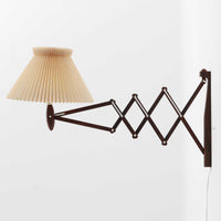 Erik Hansen(エリック・ハンセン)がデザインし、Le Klint(レ・クリント)より発表されたブラケットランプModel 332です。温かみのあるローズウッド材のアームと、職人技によるプリーツシェードの組み合わせが美しく、北欧らしい柔らかな光を演出します。アコーディオン式のアームは伸縮可能で、ベッドサイドやリビングの読書灯としても最適です。経年により味わいを増した木部とオリジナルシェードが、ビンテージならではの存在感を放ちます。ローズウッド材での展開はビンテージ品でのみ入手可能で、現行品には存在しない希少な一品です。