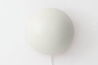 もともとへニングセンが自宅寝室のためにデザインし、1961年に発表したウォールライトで、温かみのある光を生むためシェード内面はローズ色に塗装されています。壁面でソフトな間接照明が得られ、広がり感のある空間をつくりだします。シェードが約60度可動するため、ベッドやソファーサイドの読書灯としても適しています。