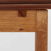 Ejner Larsen & Aksel Bender Madsenが手掛け、Naestved Mobelfabrikで製作されたエクステンションダイニングテーブルは、チーク材の天板とオーク材の脚部を組み合わせた北欧ビンテージらしい上質な佇まいが魅力です。直線的で端正なフォルムの中に、天板縁の丁寧な面取りや幕板の滑らかな造形など、当時の高い職人技が随所に感じられます。幅120cmから最大230cmまで伸長可能な構造により、日常使いから来客時まで柔軟に対応でき、空間や人数に合わせた使い方が可能です。経年変化によって深みを増した木肌の表情が、長く愛用されてきたビンテージならではの存在感を放ち、ダイニングの主役として落ち着きと品格を添えてくれる一台です。脚先には床へのダメージや汚れを防ぐためにチーク材がジョイントされており、実用性を考慮した当時の設計思想がうかがえます。また、裏面には「SKM」の刻印が確認でき、スウェーデン軍(Svenska KrigsMakten)の備品として使用されていたことを示す、背景のある希少な個体です。