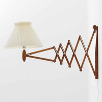 Erik Hansen(エリック・ハンセン)がデザインし、Le Klint(レ・クリント)から発表されたブラケットランプModel 332です。こちらは現行品には見られない一回り大きなサイズ感が特徴で、存在感のある佇まいを持っています。オーク材のナチュラルな風合いと、職人によるプリーツシェードが織りなす柔らかな光が空間を優しく包み込みます。アコーディオン式のアームは伸縮可能で、ベッドサイドやリビングの読書灯としても活躍する実用性の高い一品です。