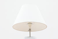 Per Lütken(ペル・ルッケン)が1980年代にデザインした「Kubus(キューブス)」シリーズのテーブルランプです。名前の通り、立方体(キューブ)をモチーフにしたホルムガードならではの厚みのある高品質なガラスが使用されており、点灯すると柔らかな光が広がり、空間に温かみと落ち着きを与えます。細いメタルの支柱が全体を引き締め、ミニマルで洗練されたデザインを際立たせています。大中小のサイズ展開がある中で、こちらは中サイズのモデルです。