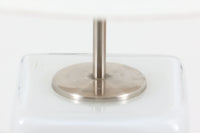 Per Lütken(ペル・ルッケン)が1980年代にデザインした「Kubus(キューブス)」シリーズのテーブルランプです。名前の通り、立方体(キューブ)をモチーフにしたホルムガードならではの厚みのある高品質なガラスが使用されており、点灯すると柔らかな光が広がり、空間に温かみと落ち着きを与えます。細いメタルの支柱が全体を引き締め、ミニマルで洗練されたデザインを際立たせています。大中小のサイズ展開がある中で、こちらは中サイズのモデルです。