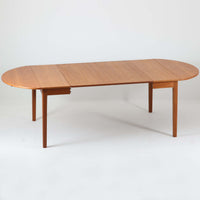 CJ Rosengaarden社によるエクステンションダイニングテーブルは、長方形の本体に両側バタフライ式の半円天板と中央拡張板2枚を備え、最大で8人がゆったりと囲める広さに対応します。温かみのあるチーク材と美しい木目、滑らかな金属レールによる開閉構造が魅力で、シーンに応じて柔軟に使える北欧ビンテージ家具の実用的な一台です。