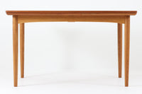 デンマークの名工Slagelse mobelvaerk社が手掛けたこちらのダイニングテーブルは、アーチ状の幕板が特徴であり、異なる素材の組み合わせが美しさを際立たせます。天板には上質なチーク材が用いられ、脚部にはナチュラルなオーク材が採用されています。また、幕板は強度と使い勝手が考慮され、通常時には4人、拡張時には6~8人が快適に使用できる設計となっています。