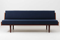 デンマークの名門家具メーカーGetama(ゲタマ)より、Hans J. Wegner(ハンス・J・ウェグナー)によってデザインされたビンテージのデイベッド「GE258」のご紹介です。チーク材のフレームに、希少な丸脚仕様が特徴的なモデルで、無駄のない美しい直線と有機的なフォルムが融合した北欧モダンデザインの代表作です。背もたれを後方に倒すことでベッドとしてもご使用いただける実用性の高い構造で、張地は落ち着いたネイビー系のファブリックで張り替え済みです。チーク材の木目が美しく、経年による味わいも感じられる逸品です。