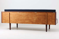 デンマークの名門家具メーカーGetama(ゲタマ)より、Hans J. Wegner(ハンス・J・ウェグナー)によってデザインされたビンテージのデイベッド「GE258」のご紹介です。チーク材のフレームに、希少な丸脚仕様が特徴的なモデルで、無駄のない美しい直線と有機的なフォルムが融合した北欧モダンデザインの代表作です。背もたれを後方に倒すことでベッドとしてもご使用いただける実用性の高い構造で、張地は落ち着いたネイビー系のファブリックで張り替え済みです。チーク材の木目が美しく、経年による味わいも感じられる逸品です。