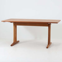 Borge Mogensen(ボーエ・モーエンセン)がFDB Moblerのために手掛けたC18ダイニングテーブルは、チーク材天板とオーク材脚部を組み合わせた北欧モダンを象徴するビンテージ家具で、直線的で端正なプロポーションと安定感のあるT字脚構造が特徴です。拡張板を備え、来客時や家族構成の変化にも柔軟に対応でき、日常使いから特別な食卓まで幅広く活躍します。現在はCarl Hansen & Son社より復刻生産されていますが、チーク材天板とオーク材脚部という素材の組み合わせは当時のビンテージ品ならではの仕様で、脚部に用いられた真鍮製の留め具も現行品とは異なる形状となっています。経年により深みを増した木肌と、実用性を重視したモーエンセンらしい設計思想、そしてビンテージならではのディテールを味わえる一台です。