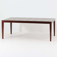 Severin Hansen Jr.によってデザインされ、Haslev社から製造されたセンターテーブルは、マホガニー材のフレームにロイヤルコペンハーゲン製Bacaシリーズのタイルをあしらった上質な一台です。精緻なカットが施された脚部と幾何学的なタイル装飾が調和し、クラフトマンシップと芸術性を兼ね備えた北欧ビンテージらしい佇まいを見せています。幅133cmのサイズ感はリビングの主役として十分な存在感を放ち、コーヒーテーブルとしてはもちろん、装飾台としてもおすすめです。