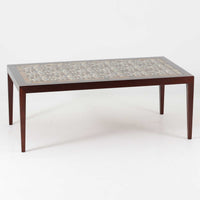 Severin Hansen Jr.によってデザインされ、Haslev社から製造されたセンターテーブルは、マホガニー材のフレームにロイヤルコペンハーゲン製Bacaシリーズのタイルをあしらった上質な一台です。精緻なカットが施された脚部と幾何学的なタイル装飾が調和し、クラフトマンシップと芸術性を兼ね備えた北欧ビンテージらしい佇まいを見せています。幅133cmのサイズ感はリビングの主役として十分な存在感を放ち、コーヒーテーブルとしてはもちろん、装飾台としてもおすすめです。