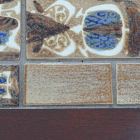 Severin Hansen Jr.によってデザインされ、Haslev社から製造されたセンターテーブルは、マホガニー材のフレームにロイヤルコペンハーゲン製Bacaシリーズのタイルをあしらった上質な一台です。精緻なカットが施された脚部と幾何学的なタイル装飾が調和し、クラフトマンシップと芸術性を兼ね備えた北欧ビンテージらしい佇まいを見せています。幅133cmのサイズ感はリビングの主役として十分な存在感を放ち、コーヒーテーブルとしてはもちろん、装飾台としてもおすすめです。