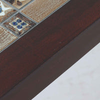 Severin Hansen Jr.によってデザインされ、Haslev社から製造されたセンターテーブルは、マホガニー材のフレームにロイヤルコペンハーゲン製Bacaシリーズのタイルをあしらった上質な一台です。精緻なカットが施された脚部と幾何学的なタイル装飾が調和し、クラフトマンシップと芸術性を兼ね備えた北欧ビンテージらしい佇まいを見せています。幅133cmのサイズ感はリビングの主役として十分な存在感を放ち、コーヒーテーブルとしてはもちろん、装飾台としてもおすすめです。