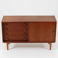 Domino Mobler社製のサイドボードは、北欧デンマークのビンテージ家具らしいシンプルかつ機能的なデザインが魅力です。チーク材を用いた温かみのある木目と深みのある色調が空間に落ち着きを与えます。左側には4杯の引き出し、右側にはスライド扉付きの収納棚を備え、食器や日用品をすっきり収めることが可能です。特徴的なスクエア型の木製ハンドルや細身の脚部が洗練された印象を与え、ダイニングやリビングでの収納家具としてだけでなく、テレビボードや飾り棚としても活躍する実用性と存在感を兼ね備えています。年月を経た風合いがより一層の魅力を引き立てる逸品です。