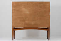 FDBモブラーでBorge mogensenの後任としてアートディレクターを務めたPoul m. Voltherによる、美しく洗練されたキャビネット。良質なマホガニー材の本体に、ビーチ材の脚部を組み合わせたコントラストが魅力です。真鍮の丸い鍵穴が特徴的な3枚の扉を備え、中央には調節可能な棚、両側には精巧な蟻継ぎが施された移動式の引き出しを配しています。下部には真鍮の俵型ハンドル付きの引き出しが3杯並び、細部へのこだわりが際立ちます。また、室内で靴を履く文化に配慮し、脚先には汚れ防止のための濃い塗装が施されています。1950年代にデザインされた本作は、先細りの脚やストレッチャーがミニマルな美しさを際立たせる一方、シンメトリーなフォルムや真鍮の装飾が伝統的なエレガンスを醸し出し、モダンとクラシックが調和した逸品です。