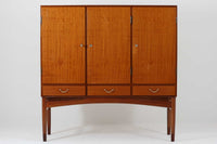 FDBモブラーでBorge mogensenの後任としてアートディレクターを務めたPoul m. Voltherによる、美しく洗練されたキャビネット。良質なマホガニー材の本体に、ビーチ材の脚部を組み合わせたコントラストが魅力です。真鍮の丸い鍵穴が特徴的な3枚の扉を備え、中央には調節可能な棚、両側には精巧な蟻継ぎが施された移動式の引き出しを配しています。下部には真鍮の俵型ハンドル付きの引き出しが3杯並び、細部へのこだわりが際立ちます。また、室内で靴を履く文化に配慮し、脚先には汚れ防止のための濃い塗装が施されています。1950年代にデザインされた本作は、先細りの脚やストレッチャーがミニマルな美しさを際立たせる一方、シンメトリーなフォルムや真鍮の装飾が伝統的なエレガンスを醸し出し、モダンとクラシックが調和した逸品です。