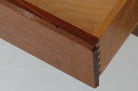 FDBモブラーでBorge mogensenの後任としてアートディレクターを務めたPoul m. Voltherによる、美しく洗練されたキャビネット。良質なマホガニー材の本体に、ビーチ材の脚部を組み合わせたコントラストが魅力です。真鍮の丸い鍵穴が特徴的な3枚の扉を備え、中央には調節可能な棚、両側には精巧な蟻継ぎが施された移動式の引き出しを配しています。下部には真鍮の俵型ハンドル付きの引き出しが3杯並び、細部へのこだわりが際立ちます。また、室内で靴を履く文化に配慮し、脚先には汚れ防止のための濃い塗装が施されています。1950年代にデザインされた本作は、先細りの脚やストレッチャーがミニマルな美しさを際立たせる一方、シンメトリーなフォルムや真鍮の装飾が伝統的なエレガンスを醸し出し、モダンとクラシックが調和した逸品です。