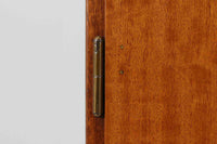 FDBモブラーでBorge mogensenの後任としてアートディレクターを務めたPoul m. Voltherによる、美しく洗練されたキャビネット。良質なマホガニー材の本体に、ビーチ材の脚部を組み合わせたコントラストが魅力です。真鍮の丸い鍵穴が特徴的な3枚の扉を備え、中央には調節可能な棚、両側には精巧な蟻継ぎが施された移動式の引き出しを配しています。下部には真鍮の俵型ハンドル付きの引き出しが3杯並び、細部へのこだわりが際立ちます。また、室内で靴を履く文化に配慮し、脚先には汚れ防止のための濃い塗装が施されています。1950年代にデザインされた本作は、先細りの脚やストレッチャーがミニマルな美しさを際立たせる一方、シンメトリーなフォルムや真鍮の装飾が伝統的なエレガンスを醸し出し、モダンとクラシックが調和した逸品です。