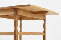 デンマークの建築家Henning Kjaernulf(ヘニング・ケアヌルフ)によってデザインされた、オーク無垢材のドロップリーフ式センターテーブルです。製造は高品質な家具で知られるEGモブラー社。無垢材ならではの美しい木目と、クラシカルで彫刻的な脚部のラインが印象的です。天板は両側に開閉式のリーフが備わっており、来客時や作業時には広げてスペースを拡張できるなど、実用性も兼ね備えています。テーブルの高さはやや高めの設計で、ソファ前に置いても手元が使いやすく、センターテーブルとして快適にお使いいただけます。必要に応じてサイドテーブルやティーテーブルとしても活躍する、用途の広い一台です。