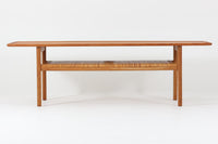 北欧より買い付けた、Hans J. WegnerによるAT10です。天板にはチーク無垢材が使われ、脚部にはオーク無垢材が採用されています。経年変化した籐の棚が特徴的で、温かみのある雰囲気を醸し出します。幅160cmというサイズ感は、3Pソファの前面に並べて使用すると、程良い距離感を保ちながら使いやすく、空間全体のバランスを整えます。縁が削り出されて丸みを帯びたデザインは、AT10の特徴であり、その独特の魅力が感じられます。