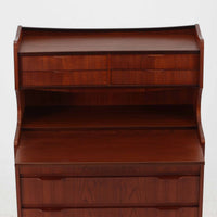 デンマーク製のチーク材によるライティングビューロです。幅85cmと程よいサイズ感で、上段には小引き出しを備え、小物や文具を整理しやすい構造になっています。中央のライティング天板は手前にスライドさせることで作業スペースが確保でき、書き物やノートPCの使用に最適です。さらに、内部には鏡が備わっており、ドレッサーとしても活用できる実用的なデザインです。下段には容量の大きな引き出しが3杯あり、衣類や書類の収納にも対応します。チーク材特有の温かみのある木目と経年による艶が味わい深く、実用性と美観を兼ね備えたビンテージ家具です。