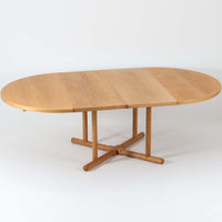 デンマークのデザイナー、Kurt Ostervig(カート・ウストヴィ)が手がけ、Jason Mobler社から発表された円形エクステンションダイニングテーブル。美しいオーク材の木目と、円形から楕円形へと広がる機能性を兼ね備えた一台です。交差する脚部の構造が彫刻的な存在感を放ち、視覚的な安定感も演出します。中央のリーフを追加することで来客時にも対応でき、実用性とデザイン性を両立。経年によるオーク材の味わい深い表情と丁寧な仕上げが、北欧ビンテージ家具ならではの魅力を感じさせます。ダイニングだけでなく、作業台としての使用にもおすすめです。