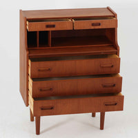 デンマーク製のビンテージライティングビューロは、上部に引き出しと仕切り棚、下部に3段のチェストを備えた実用的な設計が魅力です。チーク材の美しい木目と丸みを帯びた側面のフレームが柔らかな印象を与え、天板を引き出すことで書き物スペースとしても活用可能。コンパクトながらも多機能で、リビングや寝室での整理整頓に役立つ一台です。