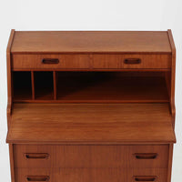 デンマーク製のビンテージライティングビューロは、上部に引き出しと仕切り棚、下部に3段のチェストを備えた実用的な設計が魅力です。チーク材の美しい木目と丸みを帯びた側面のフレームが柔らかな印象を与え、天板を引き出すことで書き物スペースとしても活用可能。コンパクトながらも多機能で、リビングや寝室での整理整頓に役立つ一台です。