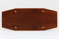 台形を基にした多角形の天板が特徴的な、美しいビンテージのセンターテーブル。心地よい木目が際立つウォールナット材の天板と、ナチュラルな風合いのビーチ材の組み合わせが、温かみのある佇まいを演出しています。天板と脚部、棚板の接続部には丸い真鍮があしらわれ、シンプルなフォルムの中に洗練されたアクセントを加えています。また、脚部をつなぐ幕板の形状も独特で、細部にまでこだわりが感じられるデザインです。デザイナーは不明ですが、細部の仕上げや素材選びから高いクオリティがうかがえる一品。モダンとクラシックが絶妙に調和した、上質なビンテージテーブルです。