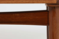 台形を基にした多角形の天板が特徴的な、美しいビンテージのセンターテーブル。心地よい木目が際立つウォールナット材の天板と、ナチュラルな風合いのビーチ材の組み合わせが、温かみのある佇まいを演出しています。天板と脚部、棚板の接続部には丸い真鍮があしらわれ、シンプルなフォルムの中に洗練されたアクセントを加えています。また、脚部をつなぐ幕板の形状も独特で、細部にまでこだわりが感じられるデザインです。デザイナーは不明ですが、細部の仕上げや素材選びから高いクオリティがうかがえる一品。モダンとクラシックが絶妙に調和した、上質なビンテージテーブルです。