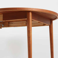 Nils Jonssonがデザインし、Troeds社より発表された円形エクステンションダイニングテーブル「Malta」です。チーク材の温かみある木目が美しく、直径110cmの天板は来客時には拡張板を追加することで大きな楕円形へと広がり、シーンに応じた柔軟な使い方が可能です。拡張板は円形では珍しく折り畳んで本体に収納することができ、機能性と利便性を兼ね備えています。脚部は細身で軽快ながら安定感があり、北欧家具らしいシンプルで機能的な構造が魅力です。日常使いはもちろん、来客時や家族の集まりにも最適で、経年による素材の風合いがビンテージならではの味わいを深めています。