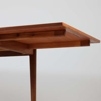 Vamo Mobelfabrikによって製造されたこちらのエクステンションダイニングテーブルは、チーク材の豊かな木目と重厚感のある質感が魅力の北欧ビンテージ家具で、幅150cmから最大270cmまで拡張可能な構造により、来客時や家族団らんの場にも柔軟に対応します。天板下に格納された2枚の中板を引き出して使用するシステムは実用性と美しさを兼ね備え、シャープなエッジと丸みを帯びた脚部が洗練された佇まいを演出します。デザイナー不明ながら、Vamo社ならではの確かな造りとDanish Controlラベルが品質の高さを物語る一台です。