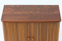 北欧デンマークで製造された、蛇腹扉が特徴的なビンテージキャビネットです。素材にはビーチ材と思われる無垢材や突板が使用されており、ステイン塗装により落ち着いたブラウンカラーに仕上げられています。前面には細かな縦ラインが連続する蛇腹扉が配され、開閉時に滑らかに動く美しい構造が魅力です。内部には棚板が一枚付属しており、収納としての機能性も十分です。丸脚や小さな丸い取っ手も北欧らしい柔らかなディテールで、リビングや玄関、寝室などさまざまな空間に自然に溶け込む一台です。