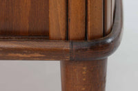 北欧デンマークで製造された、蛇腹扉が特徴的なビンテージキャビネットです。素材にはビーチ材と思われる無垢材や突板が使用されており、ステイン塗装により落ち着いたブラウンカラーに仕上げられています。前面には細かな縦ラインが連続する蛇腹扉が配され、開閉時に滑らかに動く美しい構造が魅力です。内部には棚板が一枚付属しており、収納としての機能性も十分です。丸脚や小さな丸い取っ手も北欧らしい柔らかなディテールで、リビングや玄関、寝室などさまざまな空間に自然に溶け込む一台です。