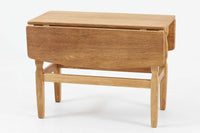 デンマークの建築家Henning Kjaernulf(ヘニング・ケアヌルフ)によってデザインされた、オーク無垢材のドロップリーフ式センターテーブルです。製造は高品質な家具で知られるEGモブラー社。無垢材ならではの美しい木目と、クラシカルで彫刻的な脚部のラインが印象的です。天板は両側に開閉式のリーフが備わっており、来客時や作業時には広げてスペースを拡張できるなど、実用性も兼ね備えています。高さ約51cmとやや高めの設計で、ソファ前に置いても手元が使いやすく、センターテーブルとして快適にお使いいただけます。必要に応じてサイドテーブルやティーテーブルとしても活躍する、用途の広い一台です。